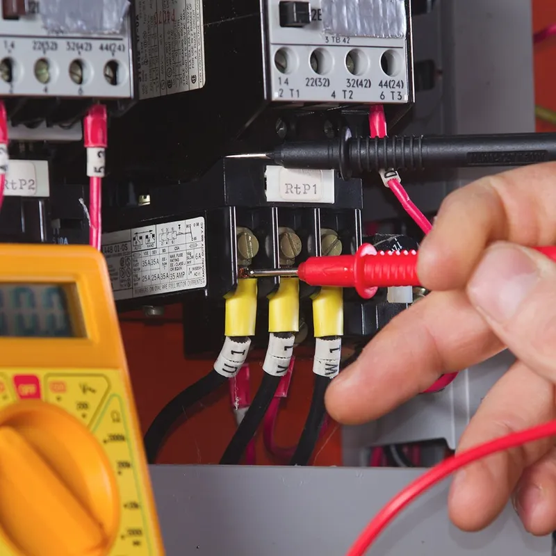 A person is working on electrical equipment